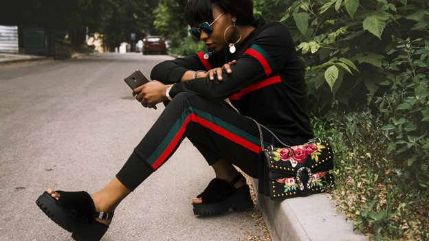 Girl wearing Gucci clothes sitting on road side